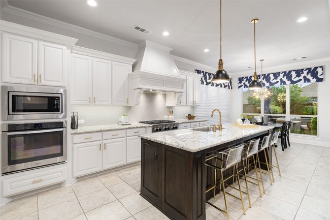 Cook up something special in this two tone kitchen with pull out spice racks, upgraded pendant lighting, large breakfast bar and upgraded granite countertops. | Image 11