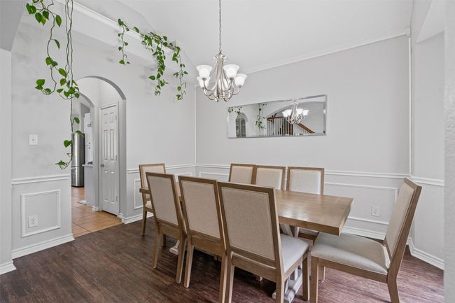 Dining room featuring a chandelier, arched walkways, crown molding, laminate floors, and vaulted ceiling | Image 8