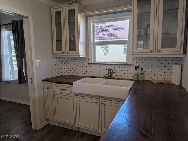 Kitchen featuring dark wood-type flooring, a sink, wood counters, baseboards, and tasteful backsplash | Image 8