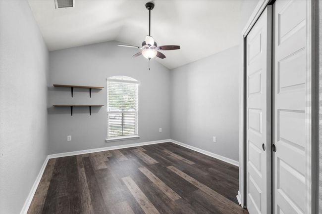 Empty room with a ceiling fan, dark wood-style floors, vaulted ceiling, and baseboards | Image 25