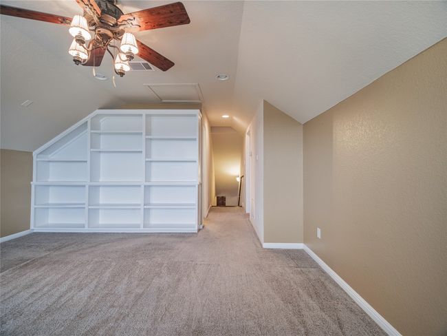 Bonus room with built in shelves, light colored carpet, ceiling fan, lofted ceiling, and baseboards | Image 35