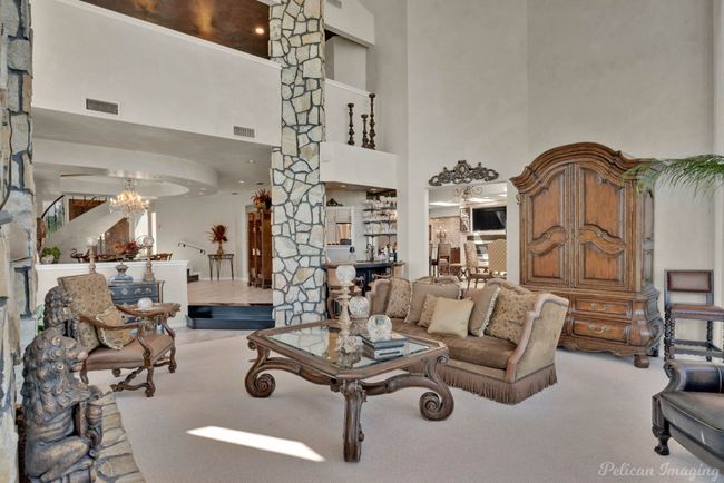 Living room featuring an inviting chandelier, a towering ceiling, ornate columns, and visible vents | Image 12