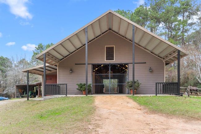 The equestrian barn is over 2, 500 square feet with an additional 547 sqft of loft storage space. The horses even have their own pantry with the 12'x24' enclosed hay storage. Additional covered storage bays for both hay and equipment are located alongside the barn. Huge, custom iron gates mark the impressive entrance to the front of the barn. A durable, industrial roll-up door makes for total security. | Image 40