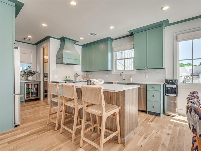 Kitchen with premium range hood, green cabinets, stainless steel appliances, backsplash, and recessed lighting | Image 11