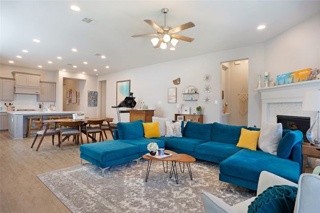 Living area featuring light wood-type flooring, ceiling fan, recessed lighting, and a glass covered fireplace | Image 6
