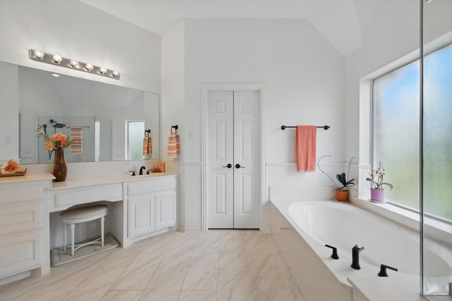 Spa-like master bath with marble-look flooring, spotless white cabinetry and dual sinks. | Image 19