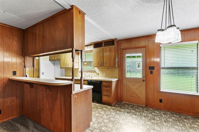 Kitchen featuring black dishwasher, a textured ceiling, brown cabinets, a peninsula, and light countertops | Image 37