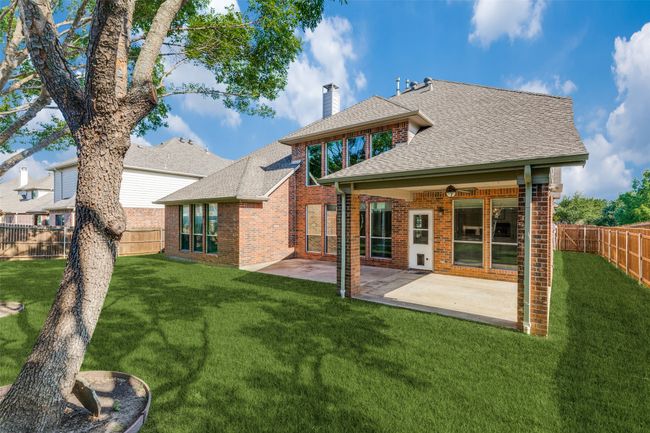 Rear view of house with brick siding, a chimney, roof with shingles, and a fenced backyard | Image 26