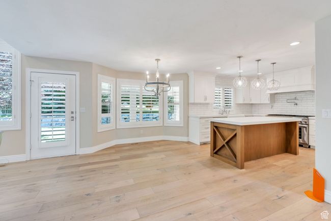 Kitchen with high end stainless steel range, a chandelier, light countertops, decorative backsplash, and white cabinetry | Image 11