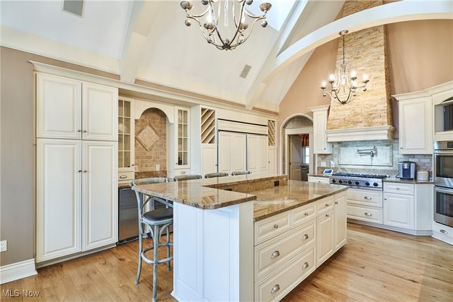 Kitchen with a kitchen breakfast bar, decorative backsplash, appliances with stainless steel finishes, arched beams, and chandeliers for the extra touch of class! | Image 7