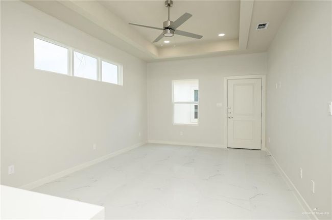 Empty room with a ceiling fan, baseboards, light marble finish flooring, a tray ceiling, and recessed lighting | Image 8
