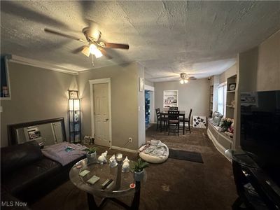 Carpeted living room with a textured ceiling and ceiling fan | Image 3