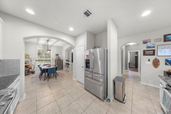 Kitchen with high end refrigerator, light tile patterned floors, arched walkways, recessed lighting, and dark stone countertops | Image 5