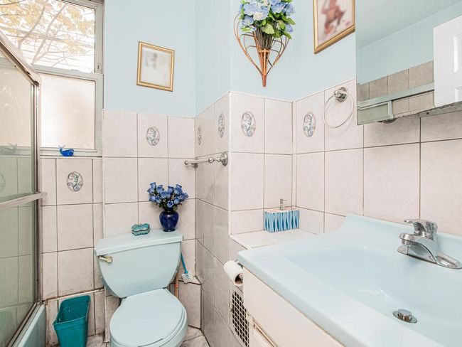 Bathroom with a sink, toilet, combined bath / shower with glass door, and tile walls | Image 9