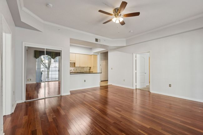 Unfurnished living room with a ceiling fan, hardwood / wood-style floors, and ornamental molding | Image 9