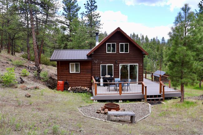 Back of house with an outdoor fire pit, a wooden deck, metal roof, and log veneer siding | Image 22