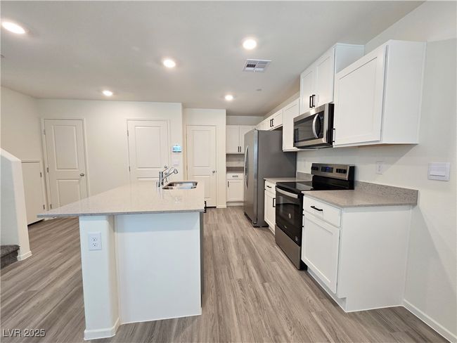 Kitchen with stainless steel appliances, a sink, light wood-style flooring, a center island with sink, and recessed lighting | Image 8