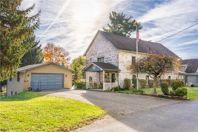 View of front facade main entrance, with a porch, a front lawn, and a garage | Image 1