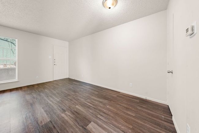 Spare room with a textured ceiling, baseboards, and dark wood-style flooring | Image 13