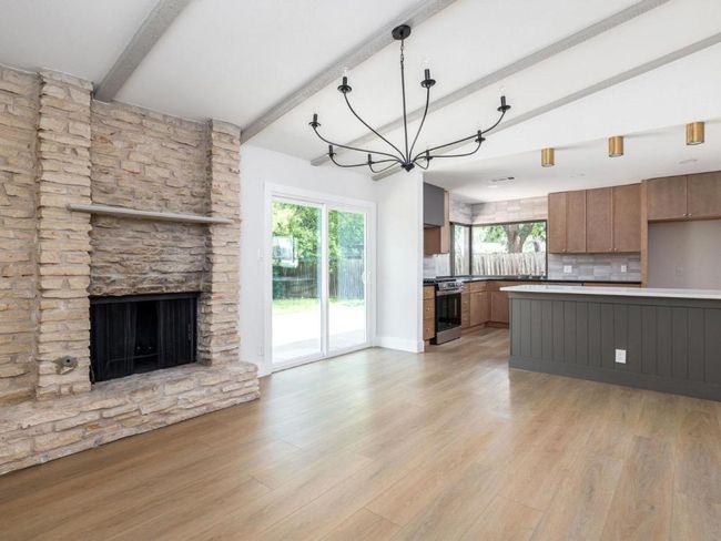 Kitchen featuring gas stove, open floor plan, beamed ceiling, backsplash, and light wood-type flooring | Image 11