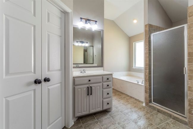 Bathroom featuring a shower stall, lofted ceiling, a garden tub, and vanity | Image 27