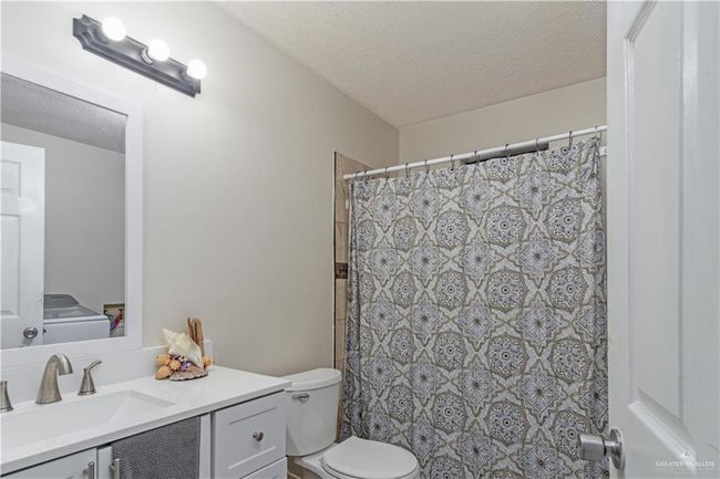 Full bathroom featuring toilet, vanity, a textured ceiling, and a shower with shower curtain | Image 11