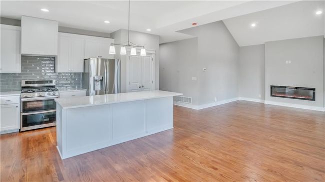 Kitchen featuring appliances with stainless steel finishes, light countertops, tasteful backsplash, white cabinets, and a center island | Image 4