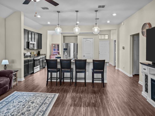 Kitchen featuring appliances with stainless steel finishes, a ceiling fan, dark wood-type flooring, a breakfast bar, and recessed lighting | Image 8