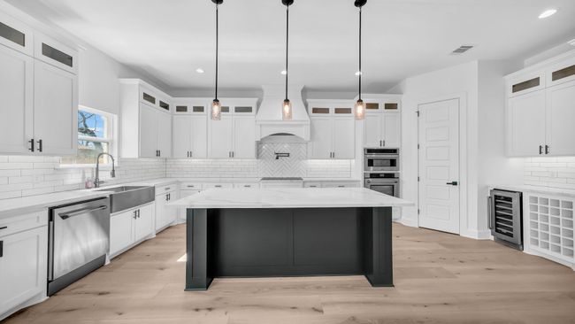Kitchen featuring visible vents, beverage cooler, a sink, appliances with stainless steel finishes, and light wood finished floors | Image 15