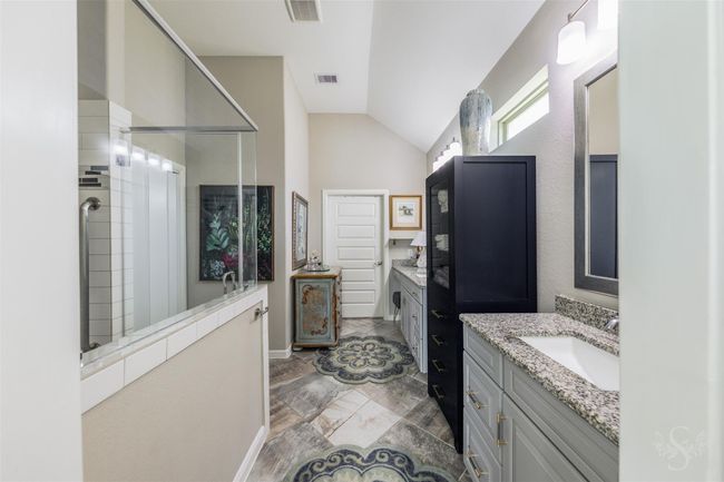 The handicap-accessible primary bathroom features a dual sink setup, offering convenience and functionality. Its thoughtful design ensures ample space for maneuverability, combining practicality with a touch of elegance. | Image 22