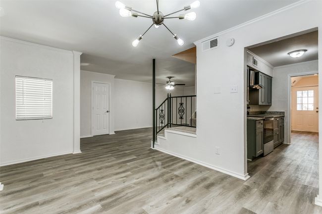 Unfurnished living room featuring ornamental molding, wood finished floors, stairs, and visible vents | Image 5