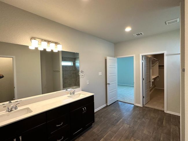 Full bath with wood finished floors, double vanity, a spacious closet, baseboards, and a shower | Image 10