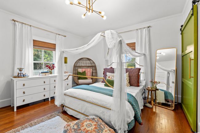 Bedroom with wood finished floors, a barn door, ornamental molding, and a chandelier | Image 20