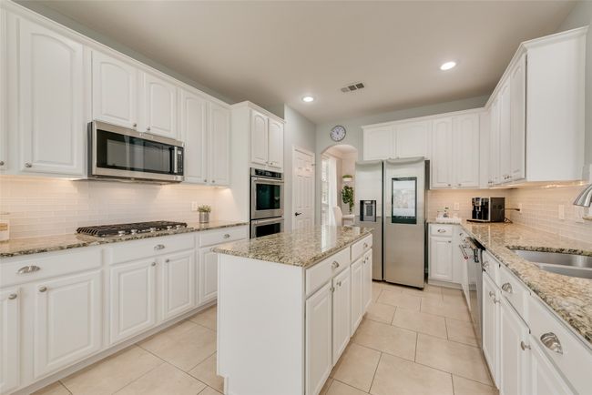 Kitchen featuring appliances with stainless steel finishes, a sink, backsplash, white cabinets, and recessed lighting | Image 13