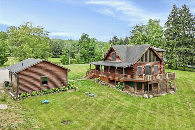 Back of property with log exterior, a wooden deck, a yard, and a shingled roof | Image 45