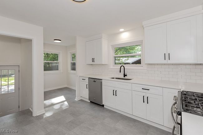 Kitchen featuring tasteful backsplash, dishwasher, sink, range with gas stovetop, and light tile patterned flooring | Image 14