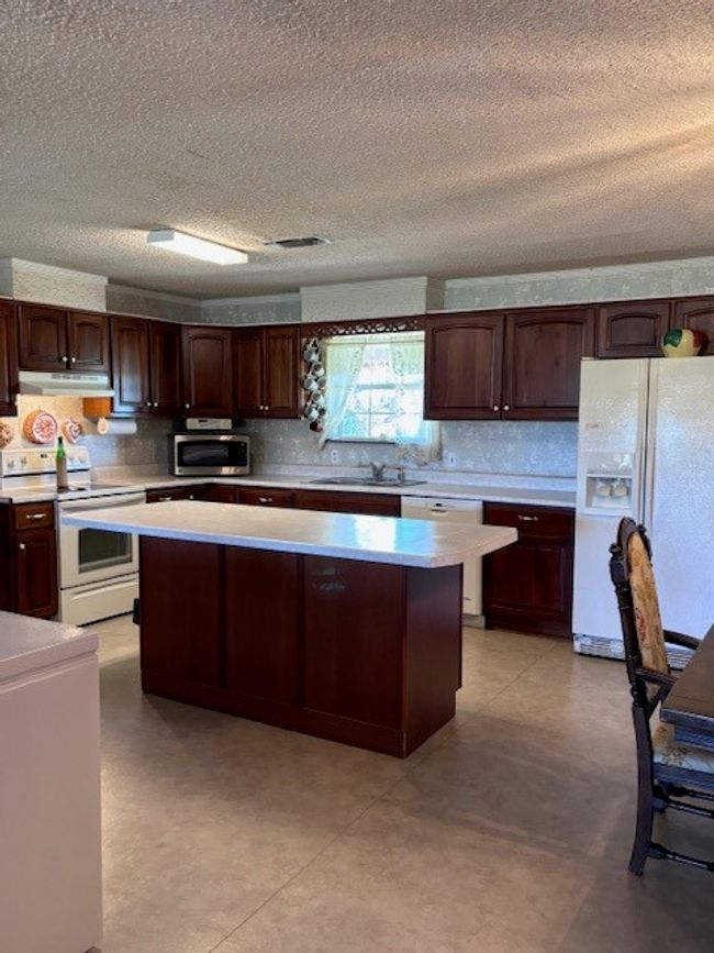 Kitchen featuring refrigerator, a center island, dishwasher, extractor fan, and stove | Image 24