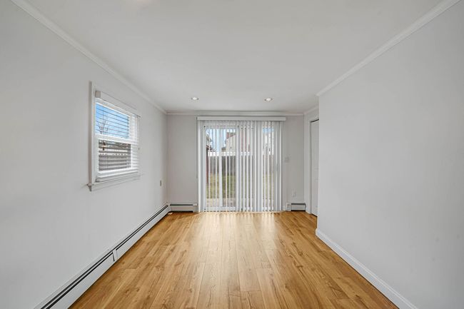 Unfurnished room with crown molding, a baseboard radiator, and light hardwood / wood-style flooring | Image 32