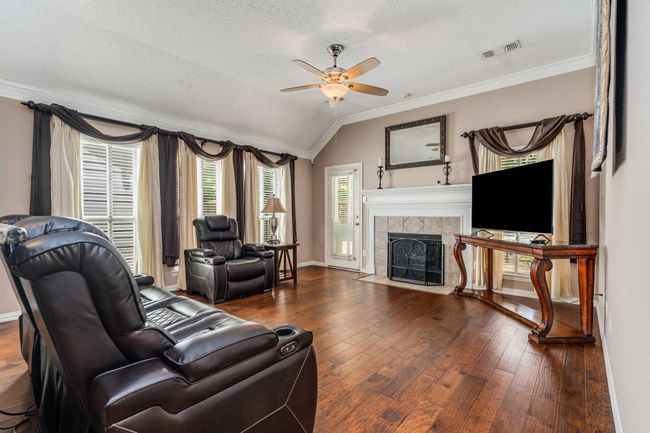 Living room with a ceiling fan, crown molding, hardwood floors, a tiled gas log fireplace, crown molding and lofted ceiling | Image 19