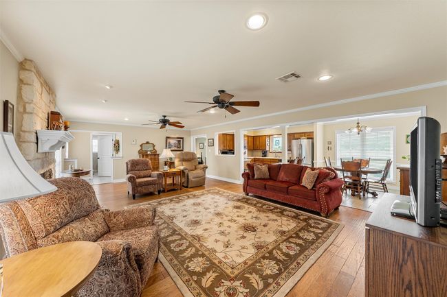 Living area featuring crown molding, light wood-style flooring, a ceiling fan, a chandelier, and recessed lighting | Image 5