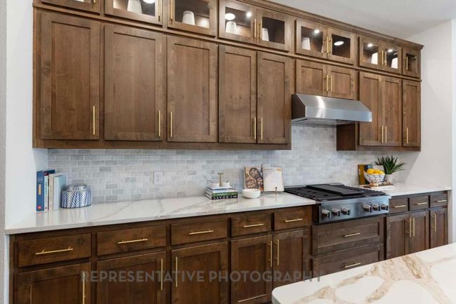 Kitchen with ventilation hood, stainless steel gas cooktop, tasteful backsplash, and light stone counters | Image 7