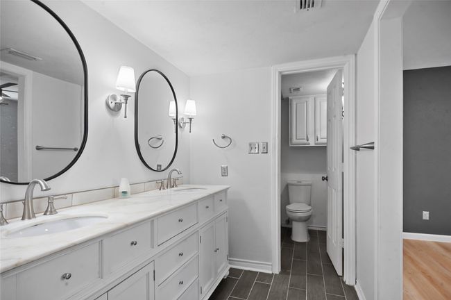 Full bathroom featuring double vanity, toilet, baseboards, and wood finished floors | Image 19