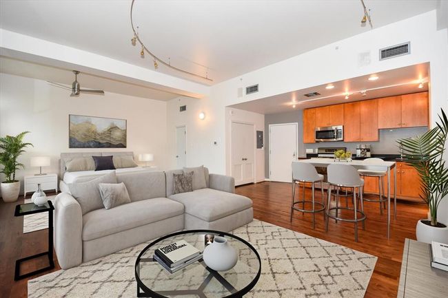 Bright and open loft-style layout featuring a sleek kitchen with dark counters top, spacious living area, and a cozy sleeping space all tied together with stylish lighting and hardwood floors throughout. | Image 4