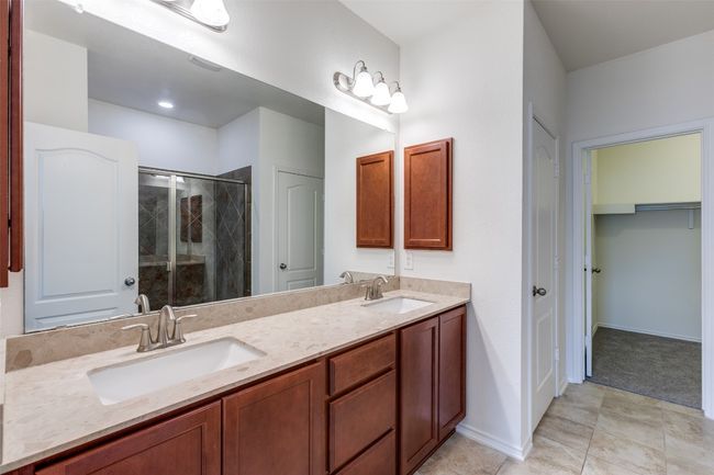 Full bathroom featuring a sink, baseboards, double vanity, and a stall shower | Image 16