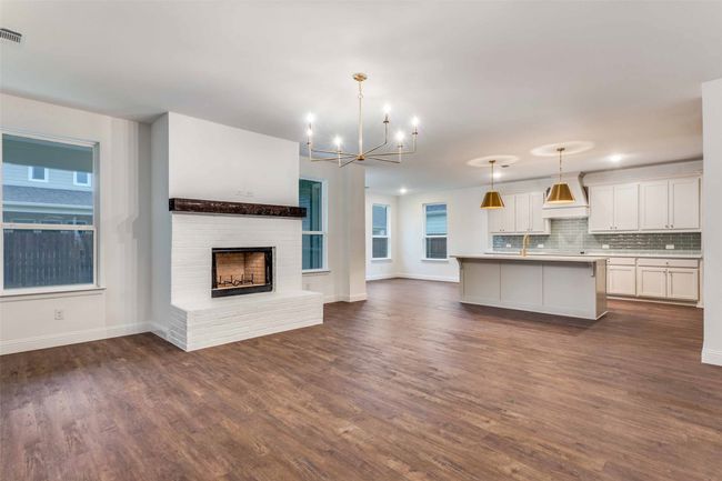 Unfurnished living room with baseboards, a notable chandelier, dark wood finished floors, and visible vents | Image 6