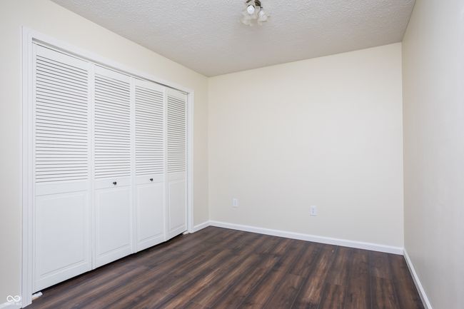 unfurnished bedroom featuring a textured ceiling, dark wood-type flooring, and a closet | Image 22