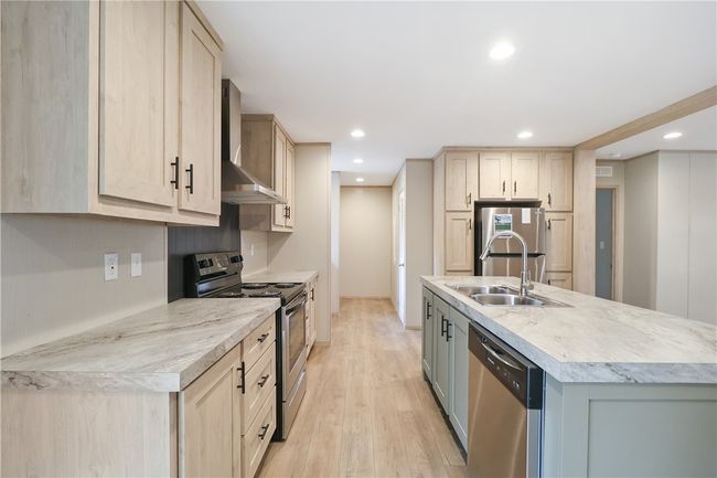 Kitchen with recessed lighting, light brown cabinetry, appliances with stainless steel finishes, a sink, and wall chimney exhaust hood | Image 9