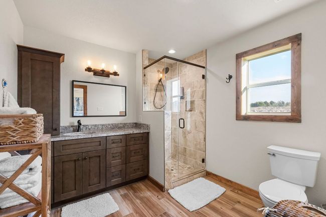 Bathroom featuring a shower stall, baseboards, wood finished floors, and vanity | Image 22