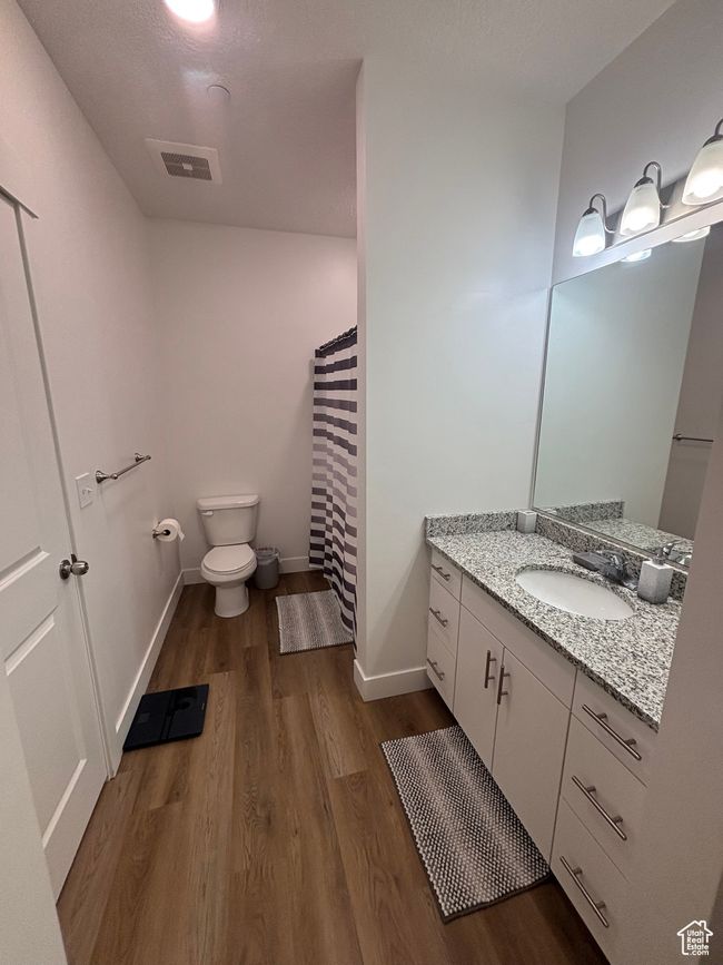 Bathroom with wood finished floors, toilet, vanity, baseboards, and a shower with shower curtain | Image 9