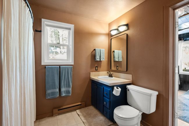 Bathroom with baseboard heating, vanity, toilet, tile patterned floors, and a textured wall | Image 22